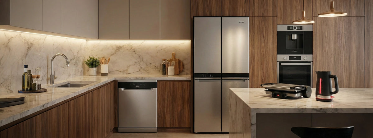 Modern kitchen with Whirlpool four-door refrigerator, Bosch built-in oven, dishwasher, coffee machine, and small kitchen appliances, featuring warm wood cabinetry and marble countertops.