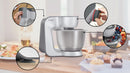 Bosch MUM58359 Series 4 on a kitchen counter with callouts for EasyArmLift, 7-speed dial, anti-slip feet and the stainless bowl mixing berries.
