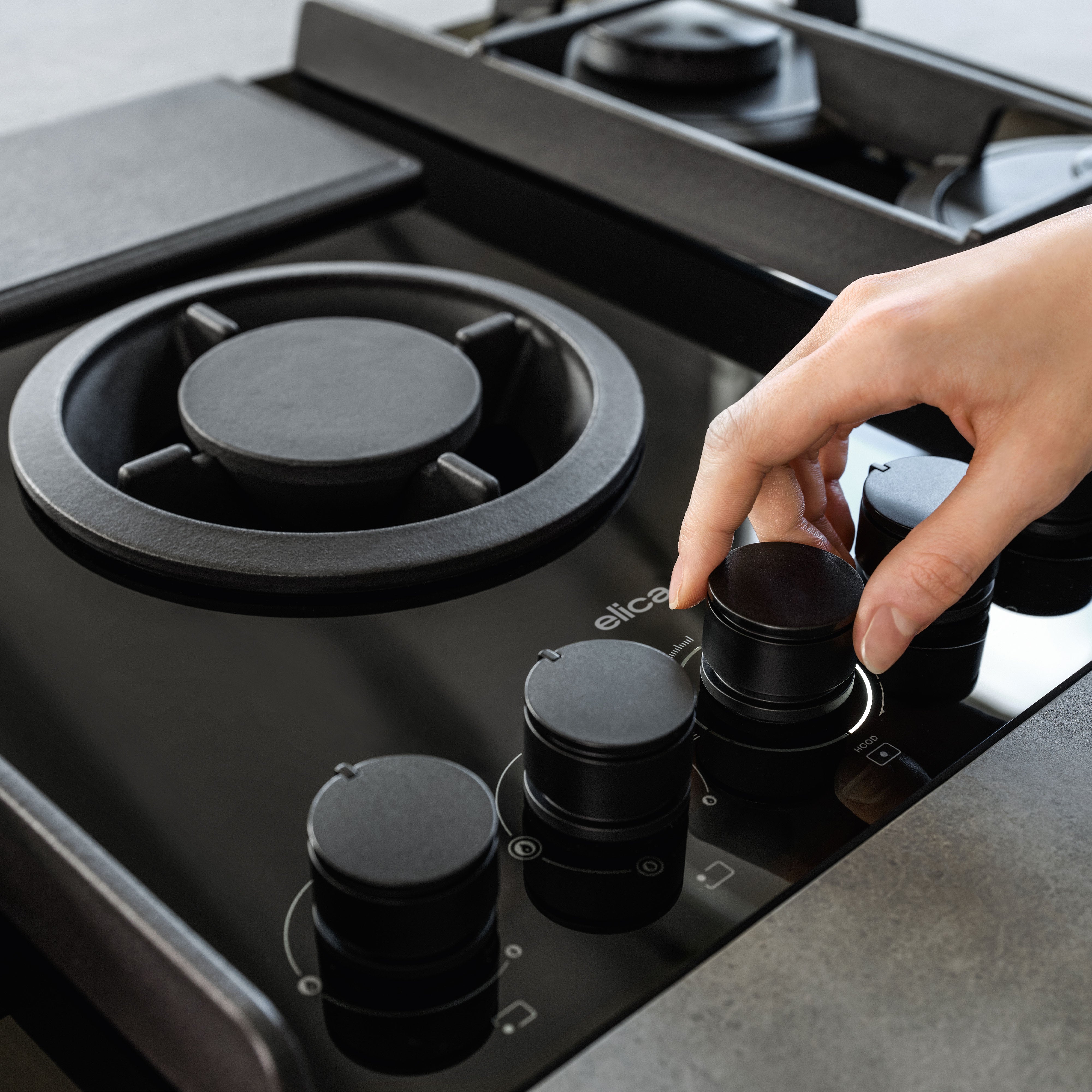 Elica NIKOLATESLA FLAME BL product angle and surface detail for the 90cm gas hob with integrated extractor in black glass.