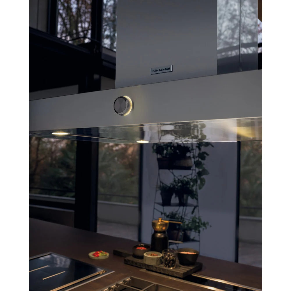 Modern kitchen with a stainless steel range hood and countertop setup.