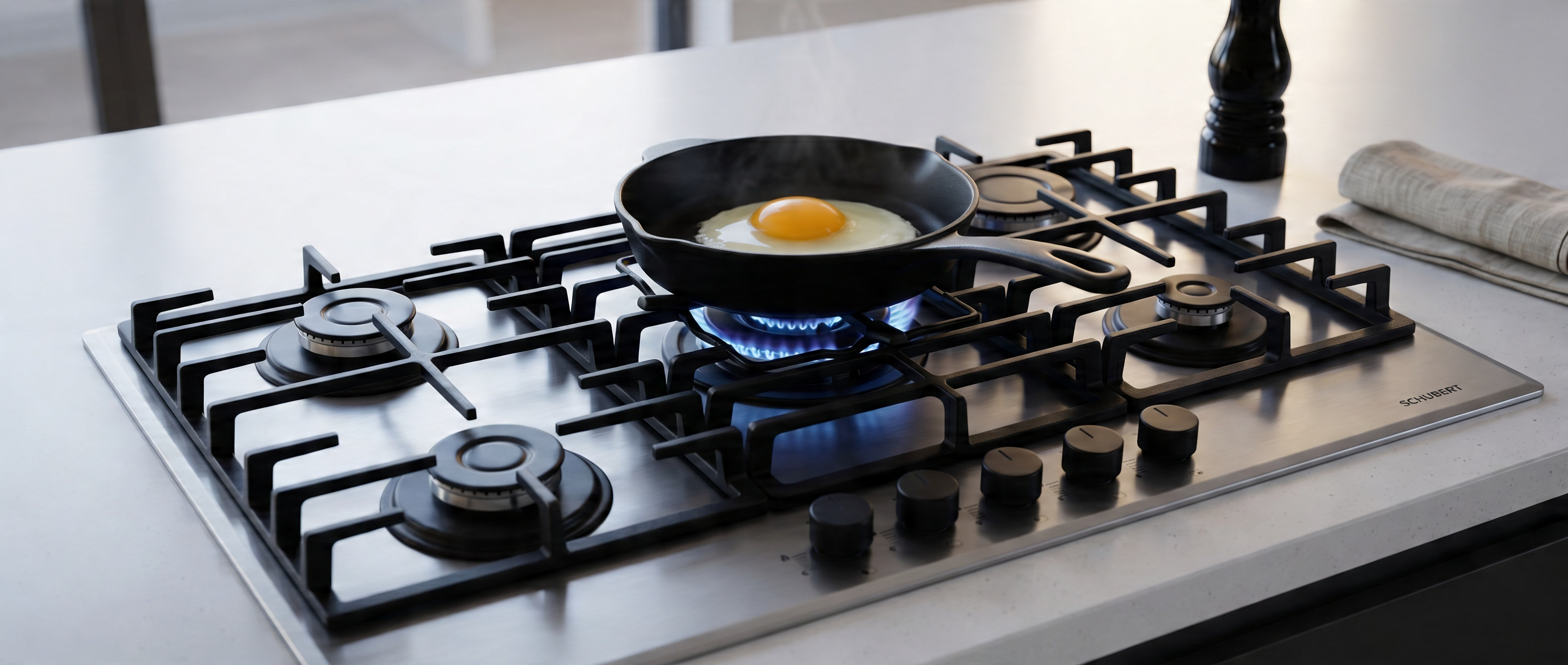 Gas stove with a frying pan containing an egg on a kitchen counter.
